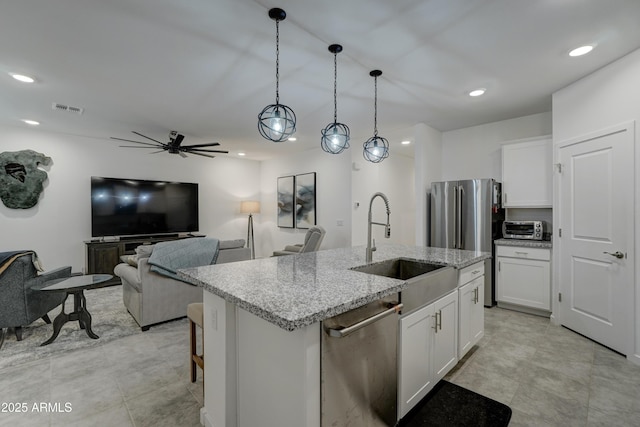 kitchen featuring pendant lighting, stainless steel appliances, light stone counters, and white cabinets