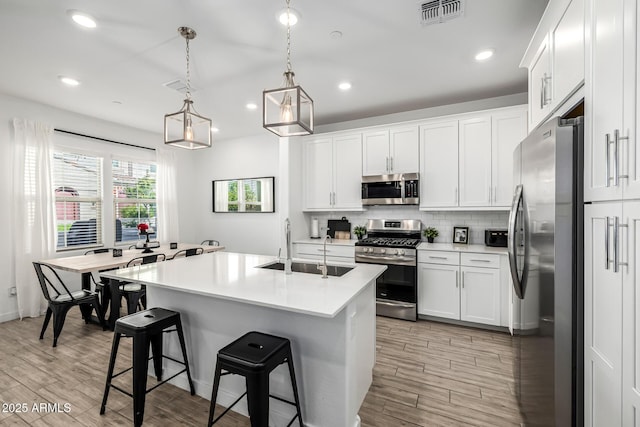 4077 S Sabrina Dr Unit 14, Chandler, AZ 85248 - kitchen featuring visible vents, a sink, stainless steel appliances, decorative backsplash, and a breakfast bar area