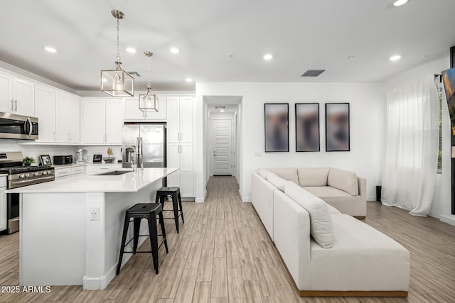 4077 S Sabrina Dr Unit 14, Chandler, AZ 85248 - kitchen with light wood-type flooring, white cabinets, a kitchen bar, stainless steel appliances, and a sink
