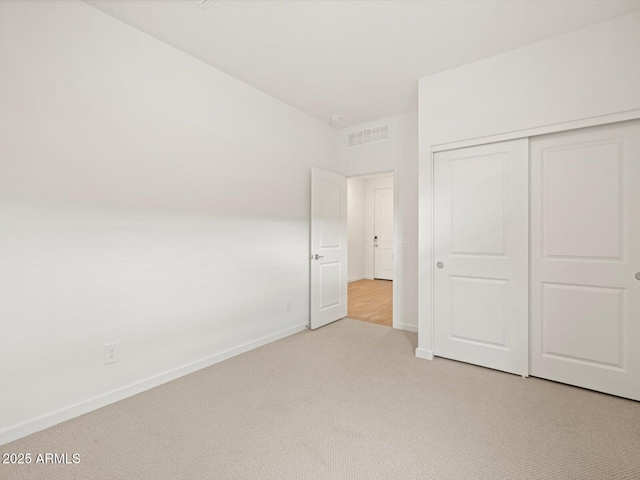 unfurnished bedroom with a closet and light carpet