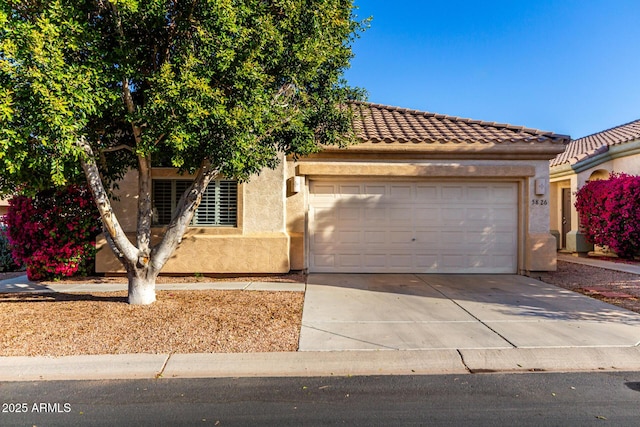 view of front facade featuring a garage, driveway, a tile roof, and stucco siding