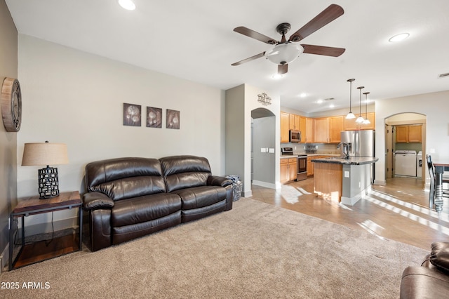 living room with light tile patterned floors, washing machine and dryer, sink, and ceiling fan