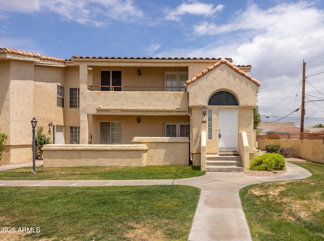 view of front facade featuring a balcony, stucco siding, and a tiled roof