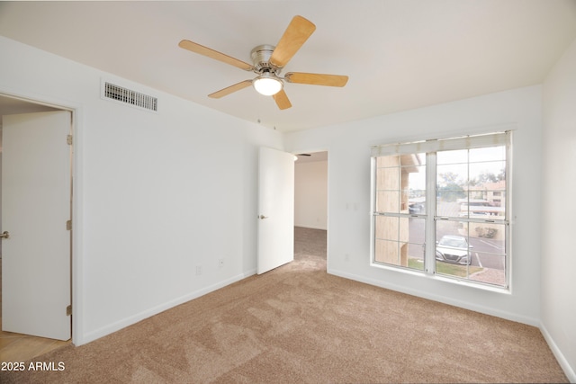 carpeted spare room with a ceiling fan and baseboards
