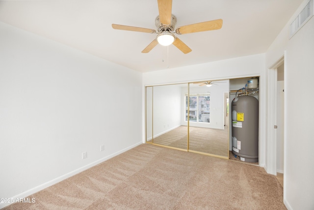 unfurnished bedroom featuring electric water heater, carpet floors, a closet, and baseboards