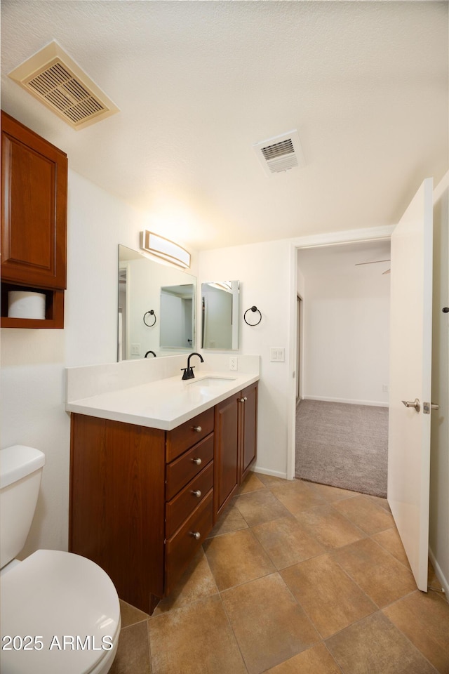 bathroom featuring toilet, vanity, and baseboards