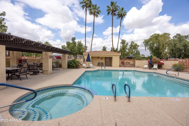 view of swimming pool with fence, a patio, and a pool with connected hot tub