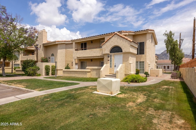 mediterranean / spanish-style home featuring stucco siding, a tile roof, and a chimney