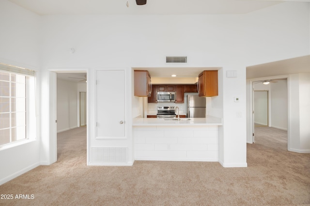 kitchen featuring stainless steel appliances, ceiling fan, and light carpet