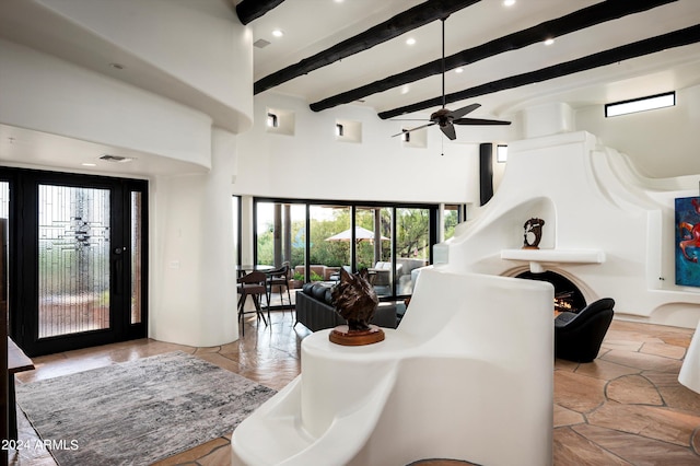 entrance foyer featuring a towering ceiling, ceiling fan, and beamed ceiling