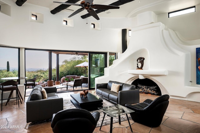 living room with ceiling fan, a towering ceiling, a fireplace, and a healthy amount of sunlight