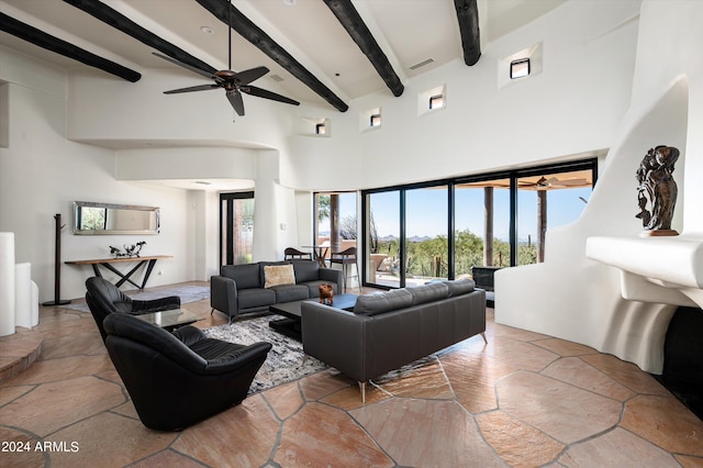 living room with ceiling fan, beamed ceiling, and a high ceiling