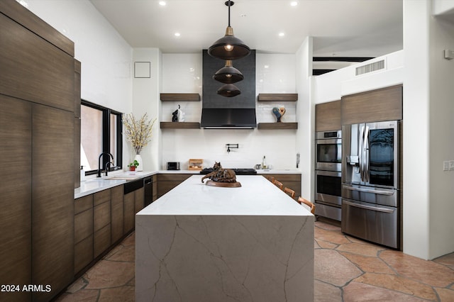 kitchen with sink, appliances with stainless steel finishes, hanging light fixtures, a kitchen island, and wall chimney exhaust hood