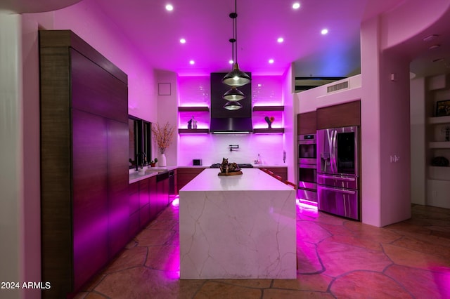 kitchen with sink, decorative light fixtures, ventilation hood, appliances with stainless steel finishes, and a kitchen island