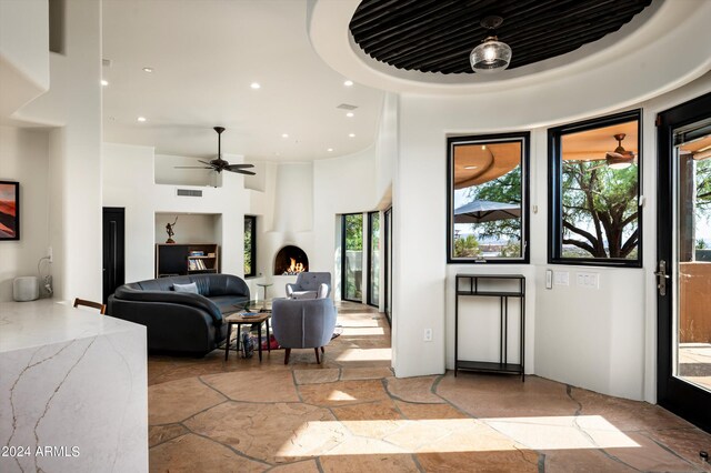 foyer entrance with ceiling fan and a large fireplace