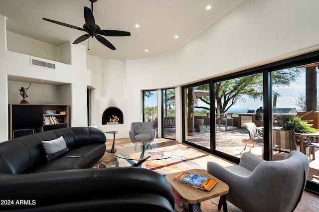 living room with a towering ceiling, a large fireplace, and a healthy amount of sunlight