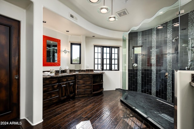 bathroom featuring wood-type flooring, a tile shower, and vanity