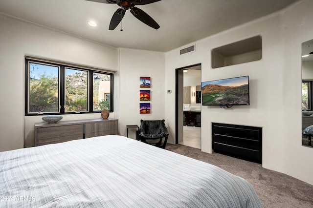 bedroom with connected bathroom, a fireplace, ceiling fan, and carpet flooring