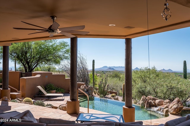 view of pool with ceiling fan, a mountain view, and pool water feature