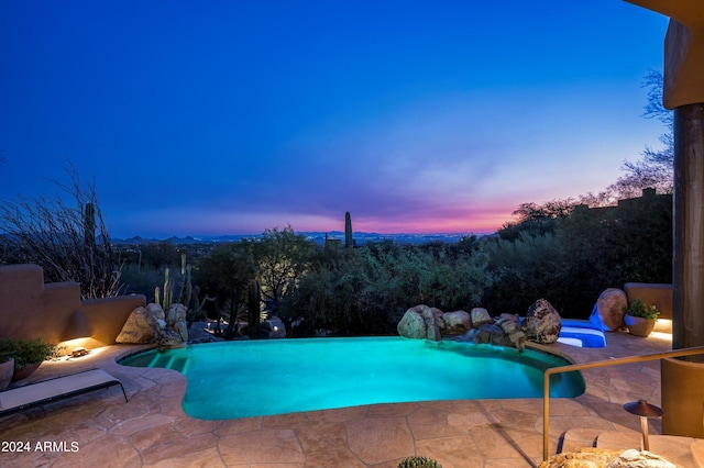 pool at dusk featuring a patio