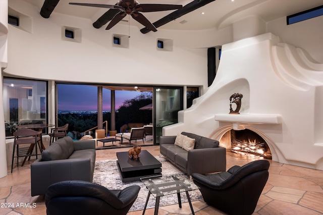 living room featuring a towering ceiling, ceiling fan, and a fireplace