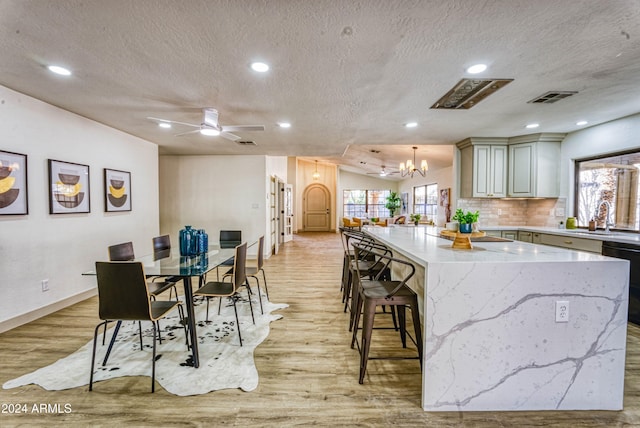 dining area with light hardwood / wood-style floors, sink, lofted ceiling, and a textured ceiling