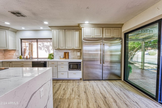 kitchen featuring cream cabinets, sink, decorative backsplash, appliances with stainless steel finishes, and light hardwood / wood-style floors