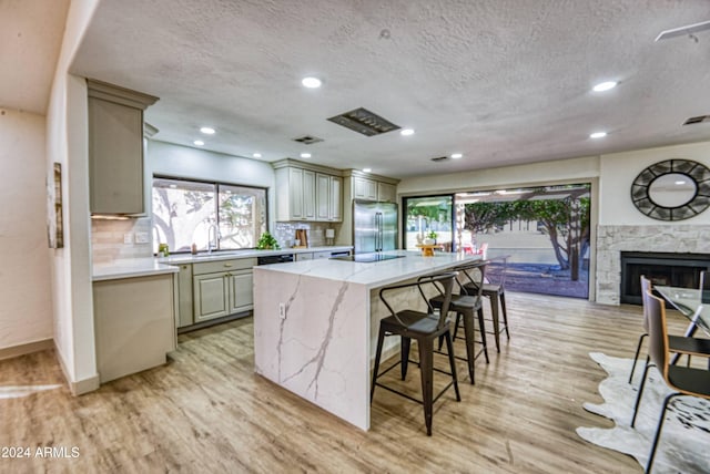 kitchen with light stone countertops, stainless steel fridge, a center island, and light hardwood / wood-style flooring