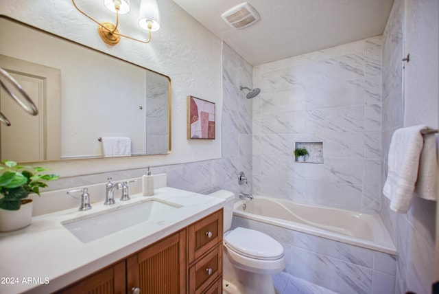 full bathroom with tiled shower / bath combo, toilet, tile walls, and vanity