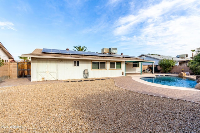 back of property with solar panels, a fenced in pool, central AC, a storage unit, and a patio area