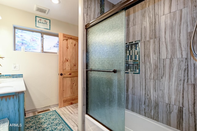 bathroom with combined bath / shower with glass door, hardwood / wood-style floors, and vanity