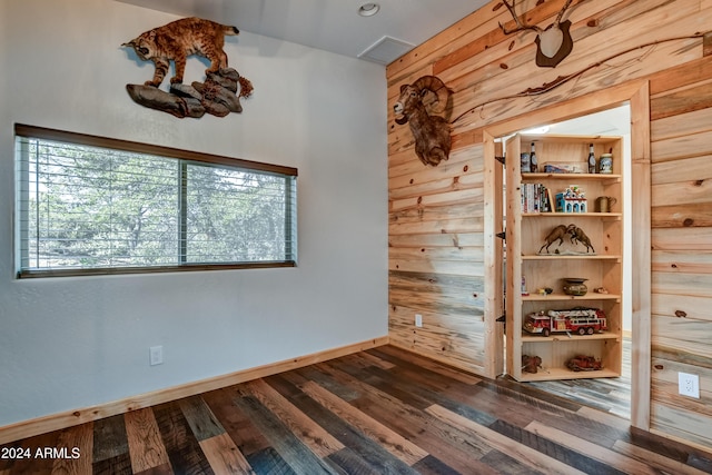 spare room featuring wood walls and dark wood-type flooring