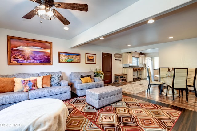 living room with beam ceiling, light wood-type flooring, and ceiling fan