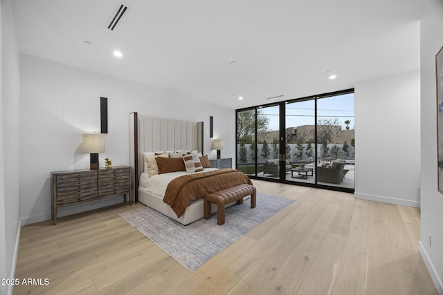 bedroom with a wall of windows, visible vents, access to exterior, and light wood finished floors