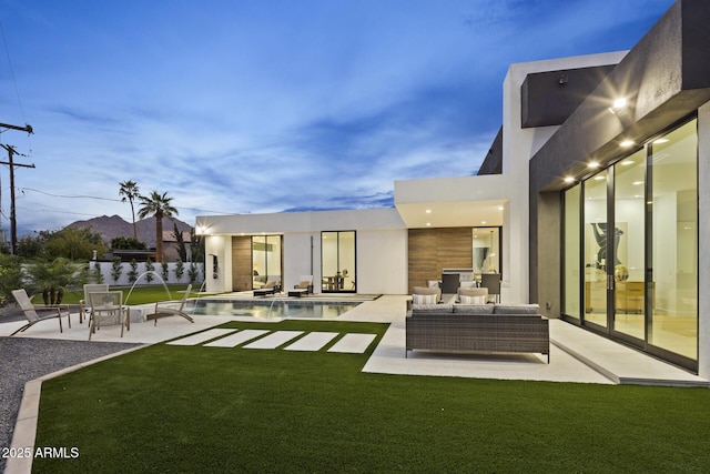 back of property featuring stucco siding, a patio, a lawn, and outdoor lounge area