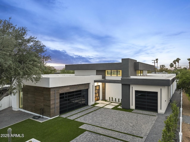 modern home featuring stucco siding, decorative driveway, and a garage