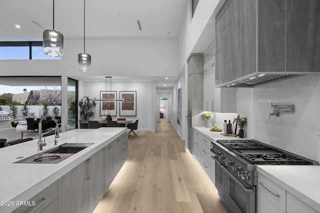 kitchen with a sink, modern cabinets, light countertops, and range with two ovens