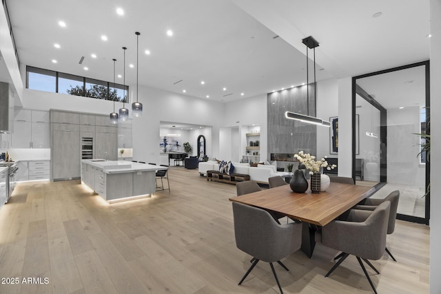 dining area with recessed lighting, a high ceiling, and light wood finished floors