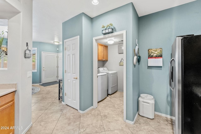 laundry room featuring cabinets, light tile patterned floors, and washing machine and clothes dryer