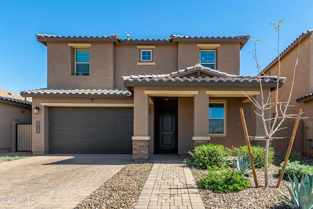mediterranean / spanish house with stucco siding, a tiled roof, and a garage