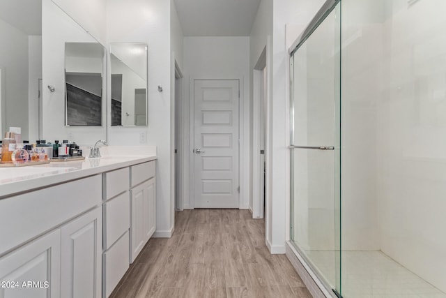 bathroom with wood-type flooring, a shower with shower door, and vanity