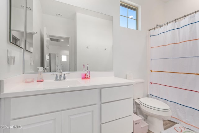 bathroom with walk in shower, vanity, and toilet