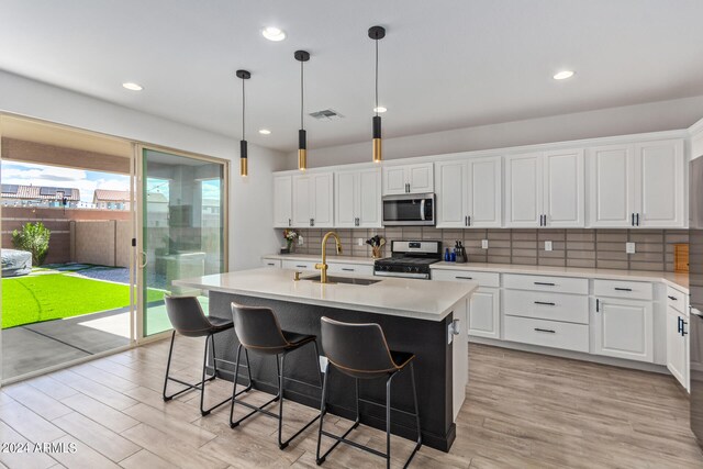 kitchen with a kitchen island with sink, sink, stainless steel appliances, and white cabinets