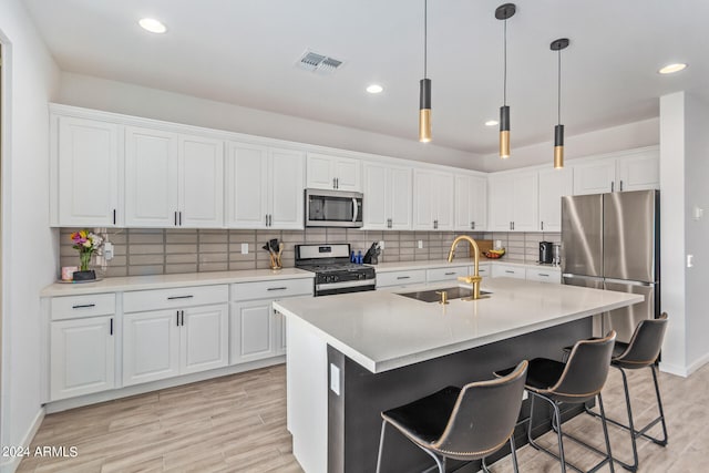 kitchen featuring sink, a center island with sink, white cabinetry, stainless steel appliances, and light hardwood / wood-style floors