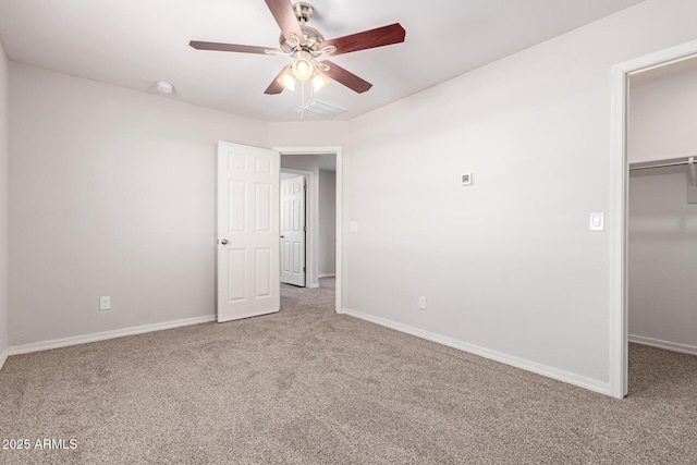 unfurnished bedroom featuring carpet floors, a walk in closet, a closet, and ceiling fan