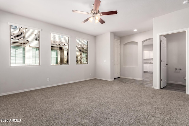 interior space with ceiling fan, ensuite bathroom, carpet flooring, and multiple windows