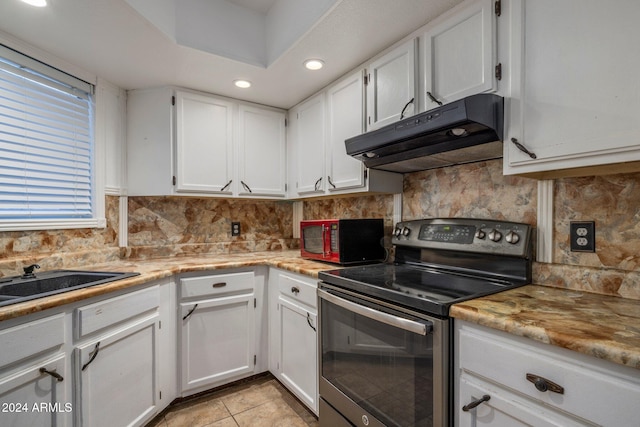 kitchen with stainless steel range with electric stovetop, backsplash, white cabinets, sink, and light tile patterned flooring