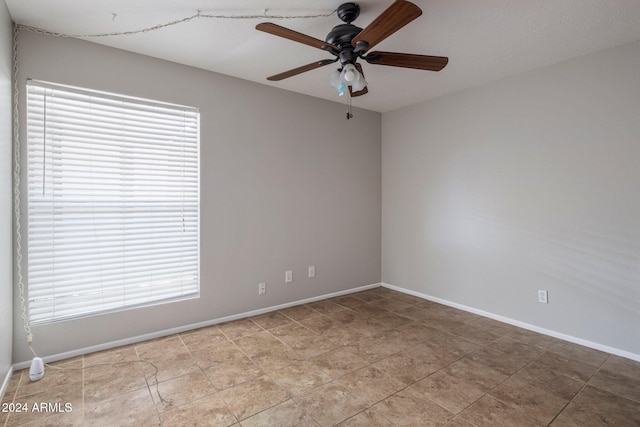 tiled empty room featuring ceiling fan