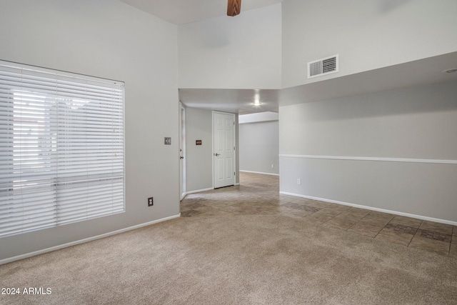 carpeted spare room featuring a high ceiling and ceiling fan