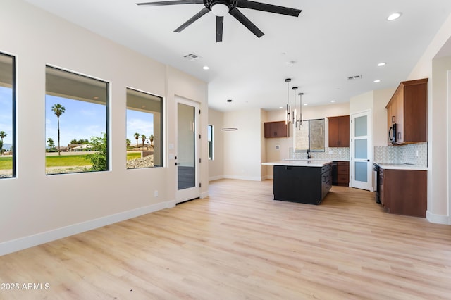 kitchen with tasteful backsplash, a kitchen island, light wood-type flooring, and decorative light fixtures